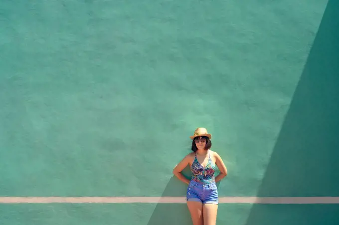 Portrait of a pretty young woman front of a training wall on a tennis