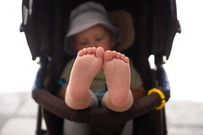 Baby feet sitting in a stroller closeup