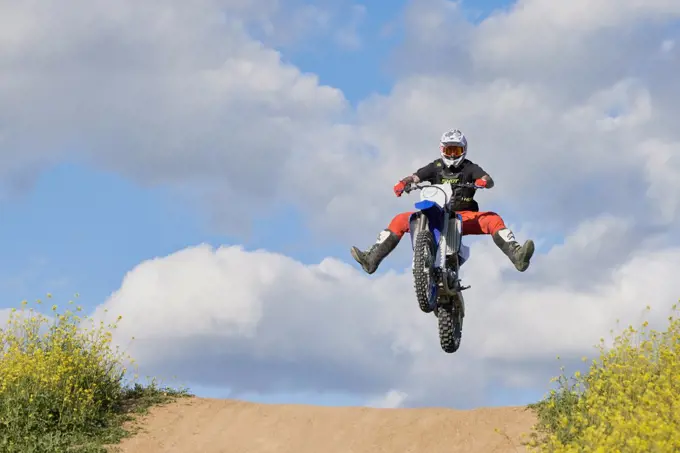 Side view of man performing stunt with motorcycle on motocross t