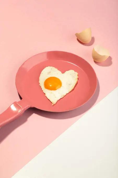 Pink frying pan and egg in heart shape. Valentine's day