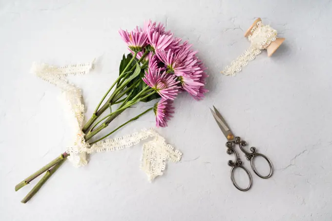 Pink flower flat lay, with scissors and lace on wooden spool