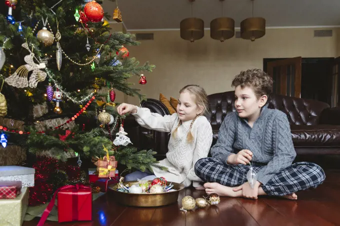 Children decorate the Christmas tree with Christmas toys.