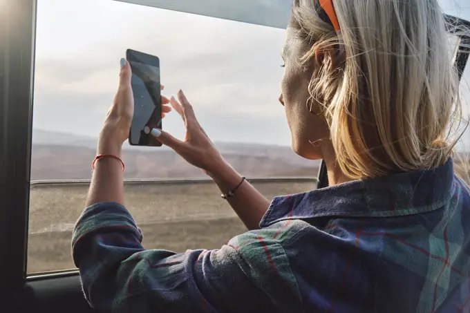 Woman taking a picture of Grand Canyon through the car window