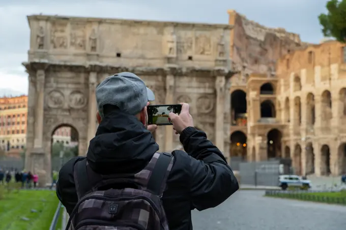 tourist man taking picture with his mobile phone at coliseum