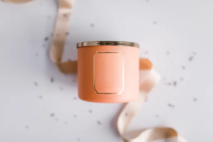 Peach colored candle in focus with ribbon and sprinkles