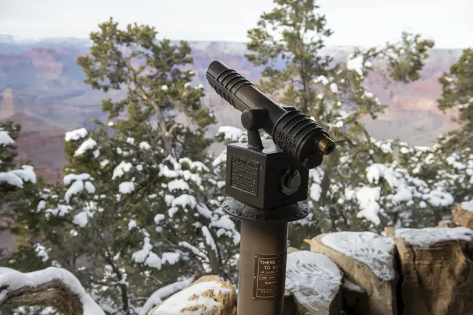 Coin-operated telescope, snow covered pine trees at the Grand Canyon