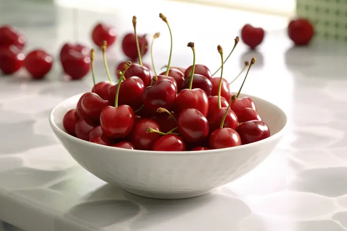Cherries on white bowl over kitchen table. Close up. Generative AI
