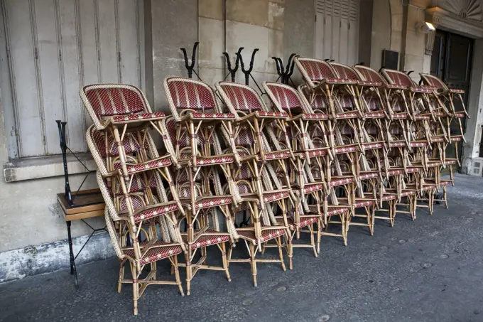 Cafe chairs stacked on a sidewalk in Paris, France.