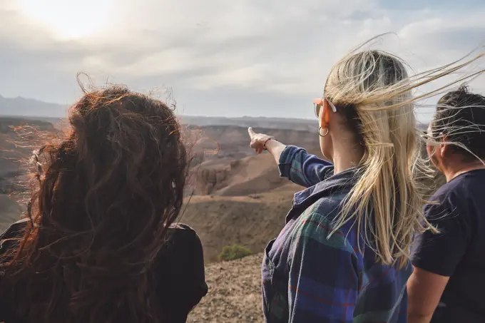 Three people looking to the Grand Canyon from a viewpoint, windy