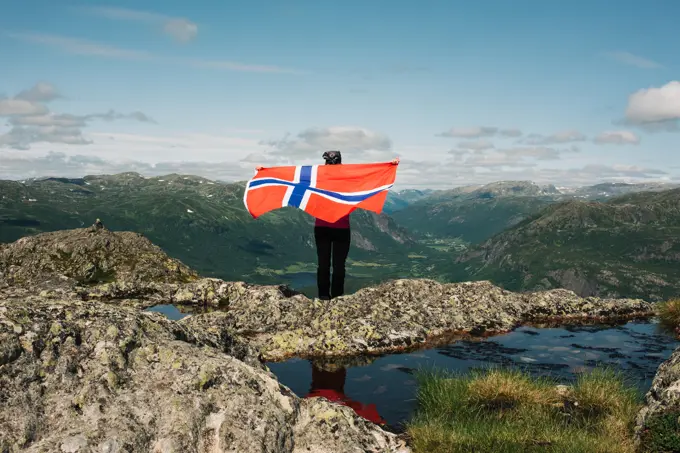 person holding the Norwegian flag in the mountains in Norway