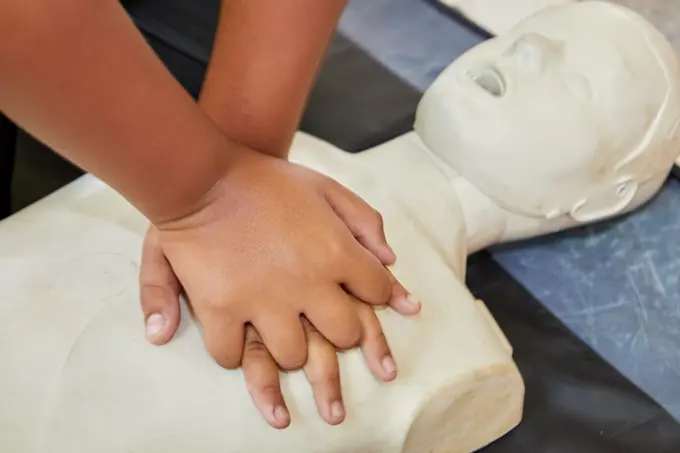 Cropped hands CPR First Aid training with CPR dummy in the classroom