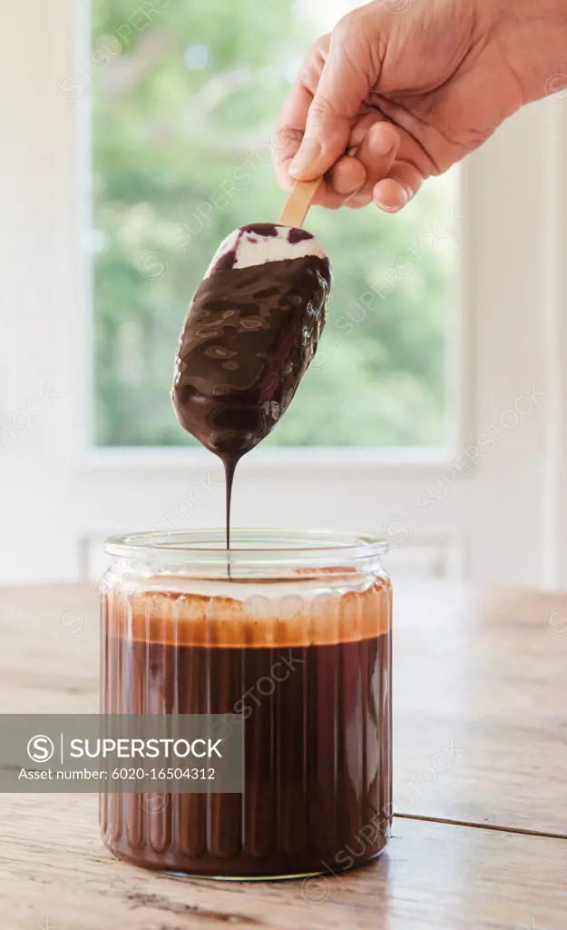 Woman dipping popsicle in chocolate