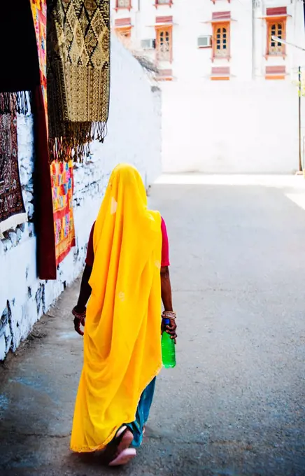 Woman walking through the city of Pushkar with a colorful yellow sari, Pushkar, India