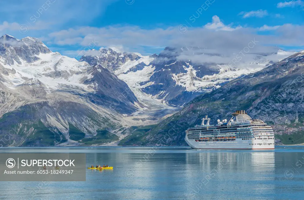 Kayakers explore the waters in Glacier Bay, while a cruise ship moves by the Topeka Glacier.