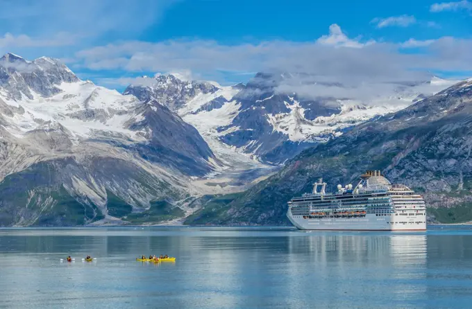 Kayakers explore the waters in Glacier Bay, while a cruise ship moves by the Topeka Glacier.