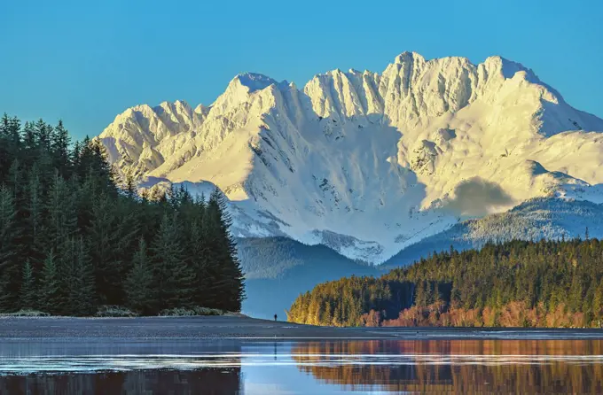 With Lions Head Mountain as a backdrop, a hiker strolls along Echo Cove Beach about 40 miles north of Juneau, Alaska 