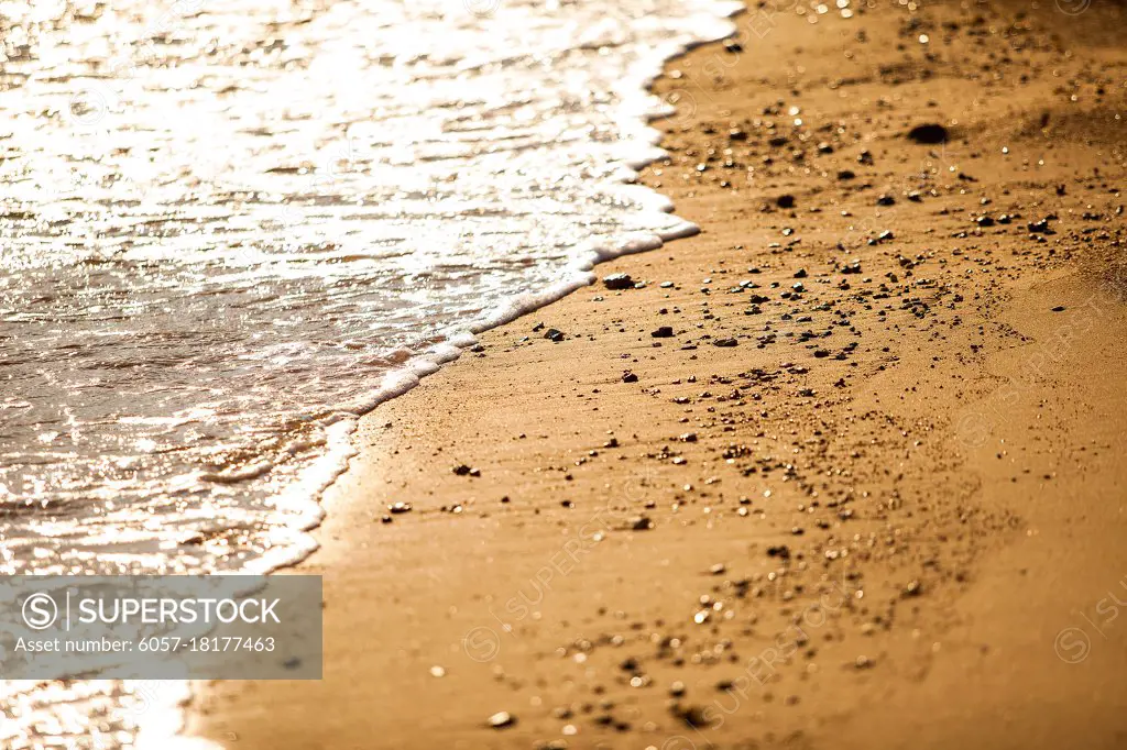 Seashore sand with water close up at sunset