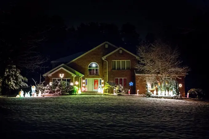 Decorated house for Christmas at night covered in snow