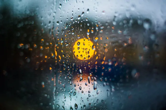 Rain drops on window. Peaceful evening or night at home when raining outside. Water drops on glass. Surface of wet glass. Water splash. City lights bokeh during the rain.