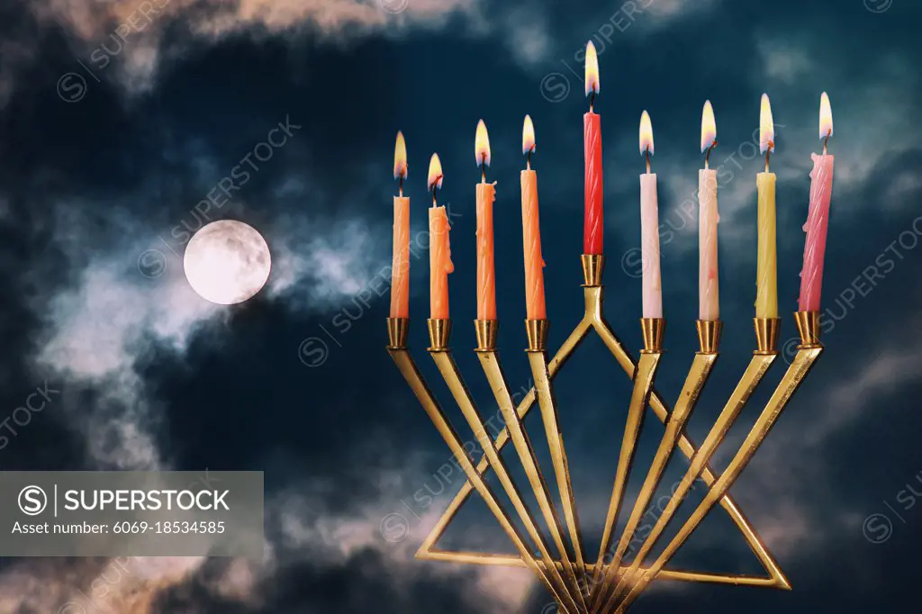 Jewish holiday Hanukkah menorah with sparks on full moon in the clouds background