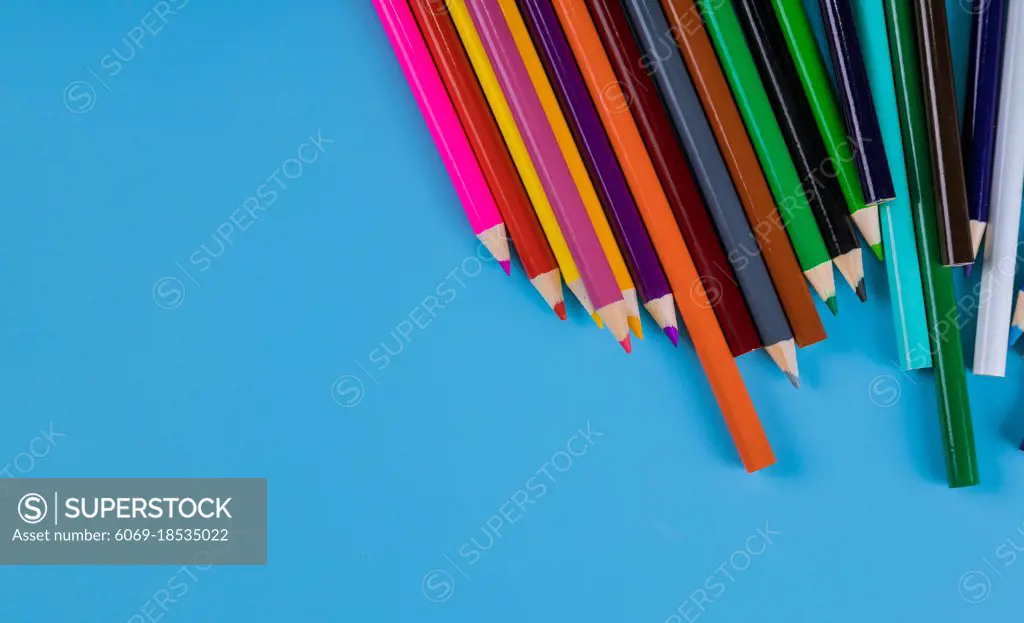 Color pencils on light blue background, school supplies