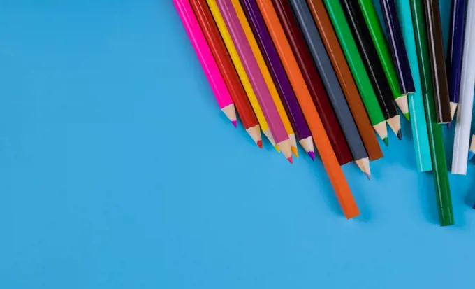 Color pencils on light blue background, school supplies