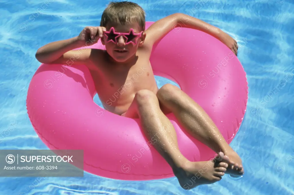 Young boy sitting on inner tube in a swimming pool