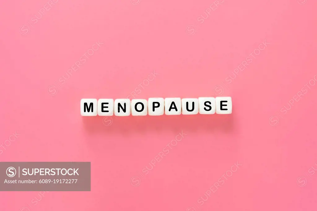 Menopause word abstract text, wooden blocks over pink background, top view