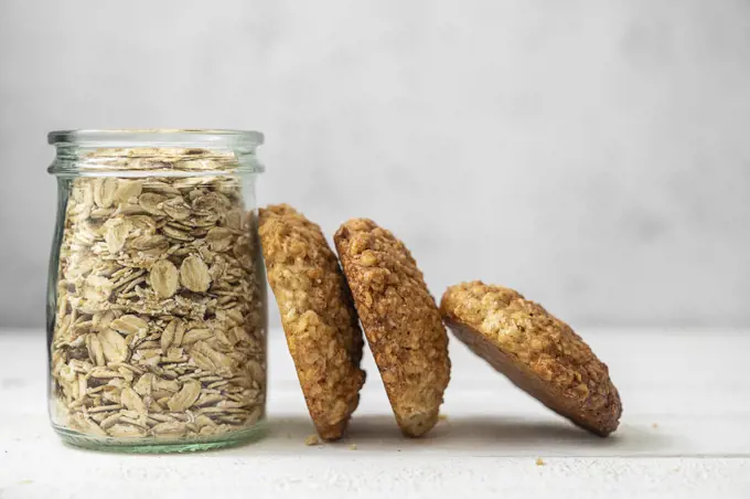 Oat cookies, healthy sweet homemade dessert and a jar with oats over bright background