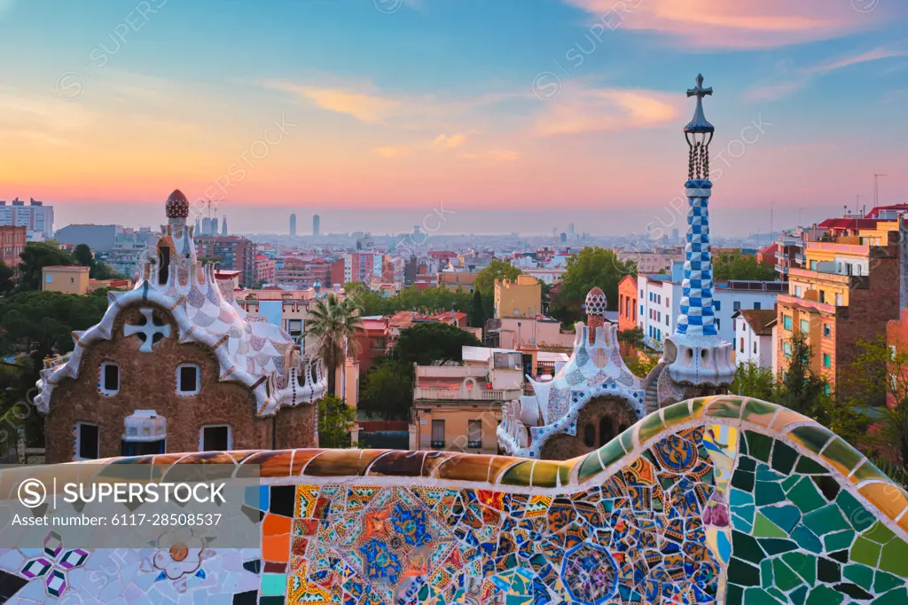 Barcelona city view from Guell Park with colorful mosaic buildings in tourist attraction Park Guell in the morning on sunrise. Barcelona, Spain