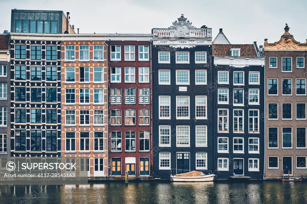 Row of typical houses and boat on Amsterdam canal Damrak with reflection. Amsterdam, Netherlands