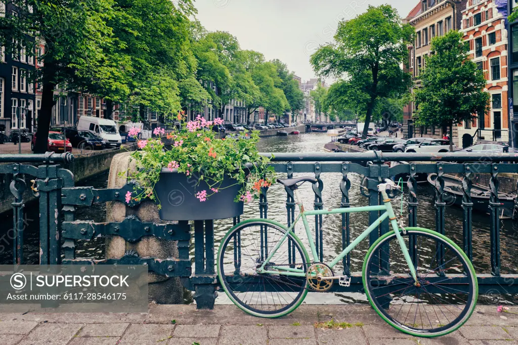 Typical Amsterdam view - Amsterdam canal with boats and parked bicycles on a bridge with flowers. Amsterdam, Netherlands