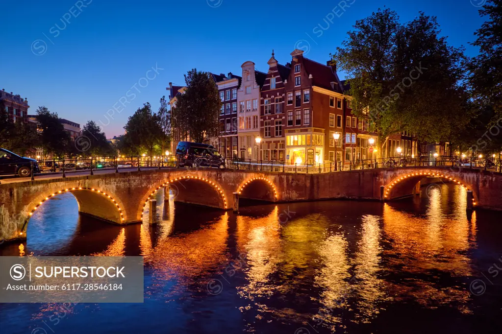 Night view of Amterdam cityscape with canal, bridge and medieval houses in the evening twilight illuminated. Amsterdam, Netherlands