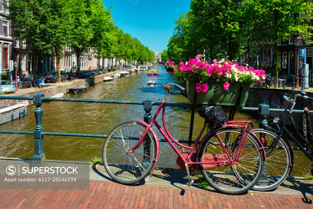 Typical Amsterdam view - Amsterdam canal with boats and parked bicycles on a bridge with flowers. Amsterdam, Netherlands