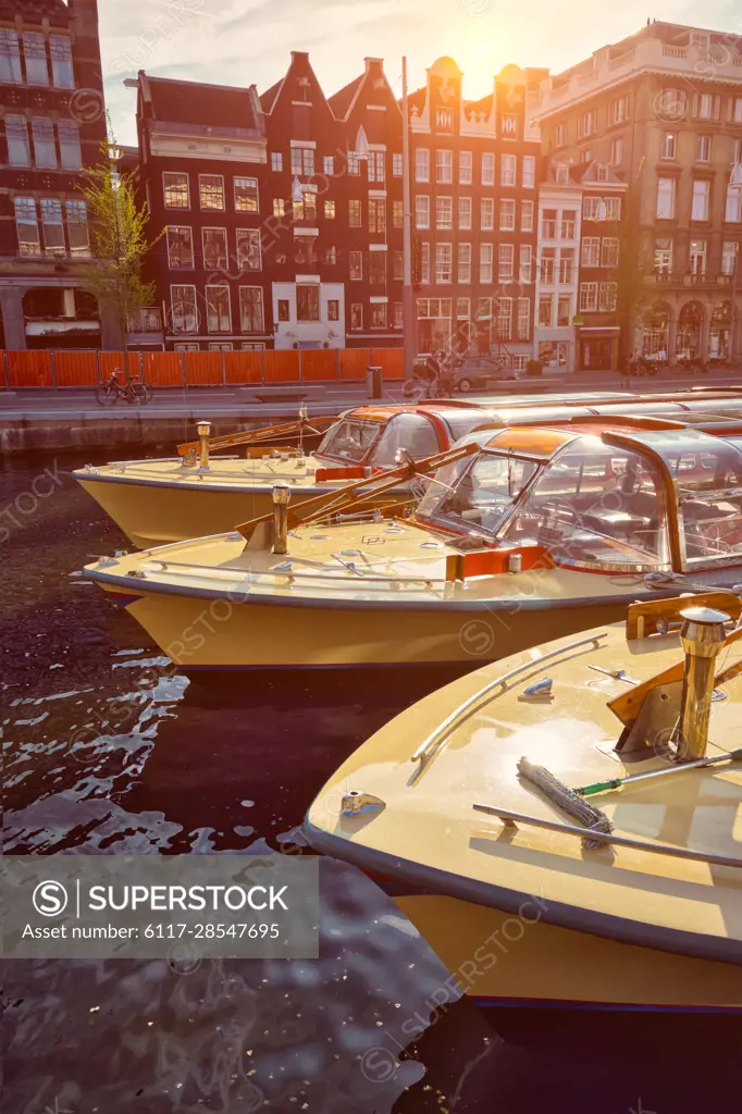 Amsterdam tourist boats in canal on sunset. Amsterdam, Netherlands