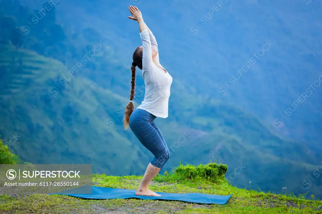 Young woman practicing yoga standing in Utkatasana exercise, Chair