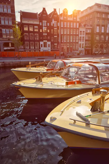 Amsterdam tourist boats in canal on sunset. Amsterdam, Netherlands