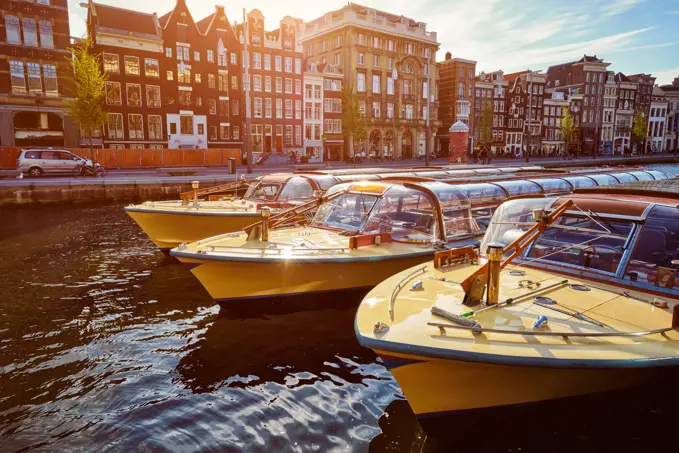 Amsterdam tourist boats in canal on sunset. Amsterdam, Netherlands