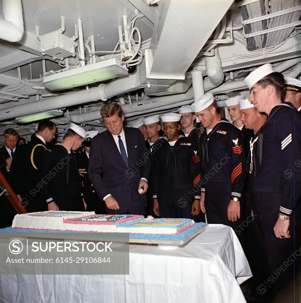 Visit to the Atlantic Fleet: Presentation of a cake to President Kennedy aboard the USS Northampton (CC-1). President John F. Kennedy (center left) admires a cake prepared to commemorate his visit aboard the cruiser USS Northampton (CC-1), command ship of the U.S. Atlantic Fleet, at sea off the coast of Virginia and North Carolina. Naval Aide to the President Captain Tazewell Shepard, Jr. stands at left; Commissary Steward Petty Officer First Class, Horace L. Medders, USN (one of the sailors who baked the cake), stands fourth from right; crew members look on. President Kennedy boarded the ship earlier that day at Naval Air Station, Norfolk, Virginia for an overnight cruise to view fleet exercises.