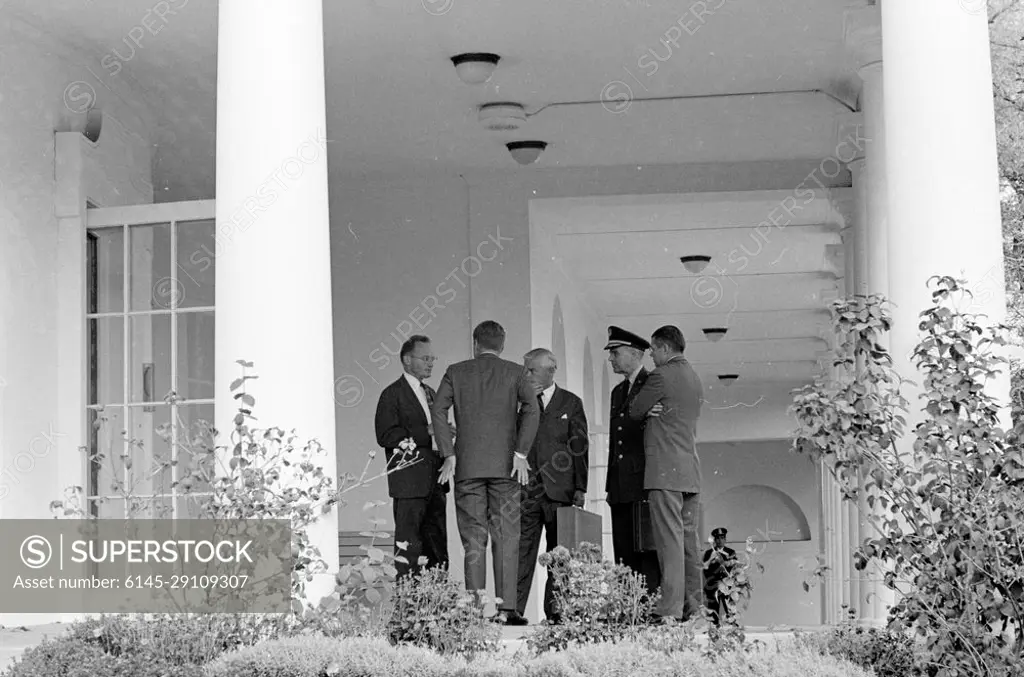 National Security Council Executive Committee (EXCOMM) Meeting, 10:10AM. President John F. Kennedy (back to camera) speaks with members of the Executive Committee of the National Security Council (EXCOMM) in the West Wing Colonnade outside the Oval Office, White House, Washington, D.C. (L-R) Special Assistant to the President for National Security McGeorge Bundy, President Kennedy, Assistant Secretary of Defense for International Security Affairs Paul Nitze, Chairman of the Joint Chiefs of Staff General Maxwell D. Taylor, and Secretary of Defense Robert S. McNamara. The President met with members of the EXCOMM that day regarding the crisis in Cuba.