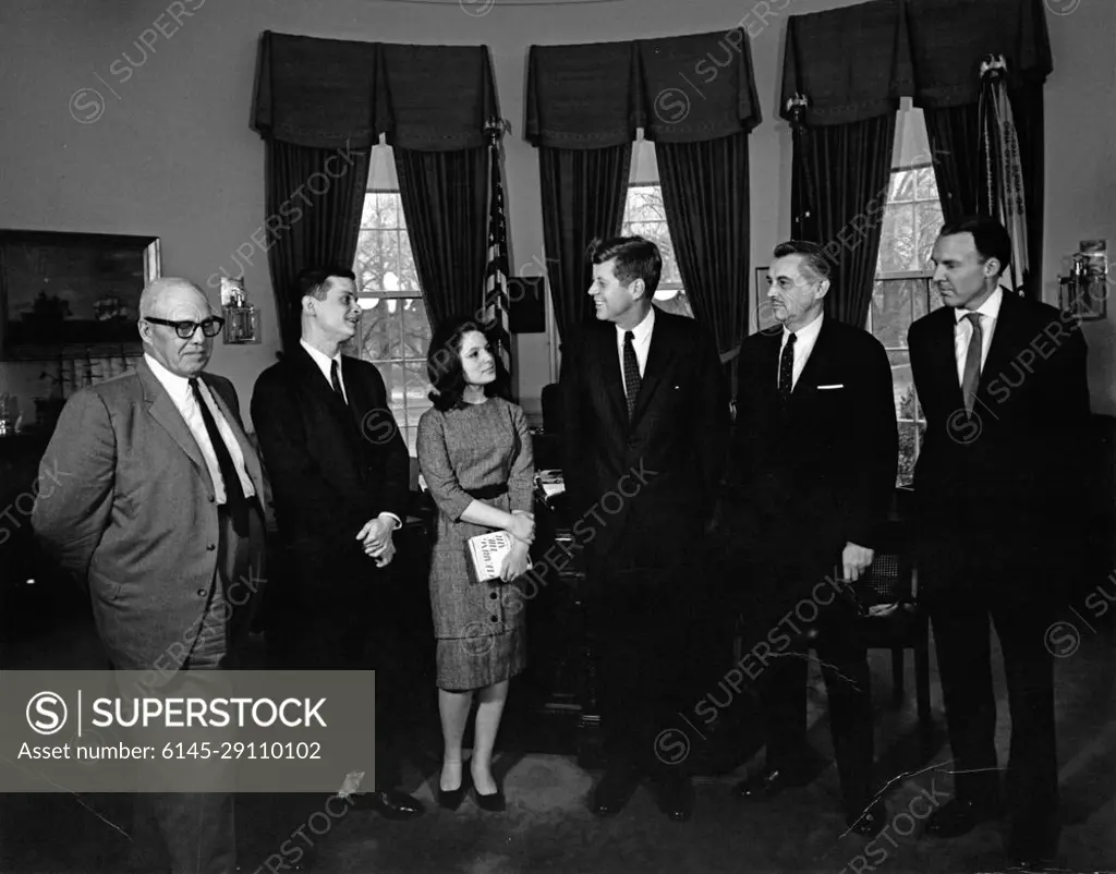 Visit of Carla Lipsig and Richard C. Frazier, winners of the ABC Edward P. Morgan Essay Contest, 11:15AM. President John F. Kennedy visits with the first-place winners of the 1962 American Broadcasting Company (ABC) Edward P. Morgan Essay Contest on the subject of Youths Challenge in the Labor Market of the 60s. Left to right: President of the American Federation of Labor and Congress of Industrial Organizations (AFL-CIO), George Meany; contest winner, Richard C. Frazier, of Queens College; contest winner, Carla Lipsig, of Brandeis University (holding a copy of Edward P. Morgans book Clearing the Air); President Kennedy; journalist and ABC commentator, Edward P. Morgan; President of the ABC Radio Network, Robert R. Pauley. Oval Office, White House, Washington, D.C.