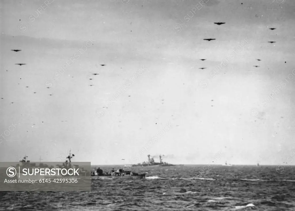 The Royal Navy during the Second World War- Operation Overlord (the Normandy Landings)- D-day 6 June 1944 Glider borne troops passing over units of the Royal Navy on their way to the invasion beaches of Normandy. In the background are the battleships HMS WARSPITE and HMS RAMILLIES whilst an unidentified destroyer sails in the middle distance. Photograph taken from the cruiser FROBISHER, which had helped bombard the enemy coastal positions during the week before D-Day.