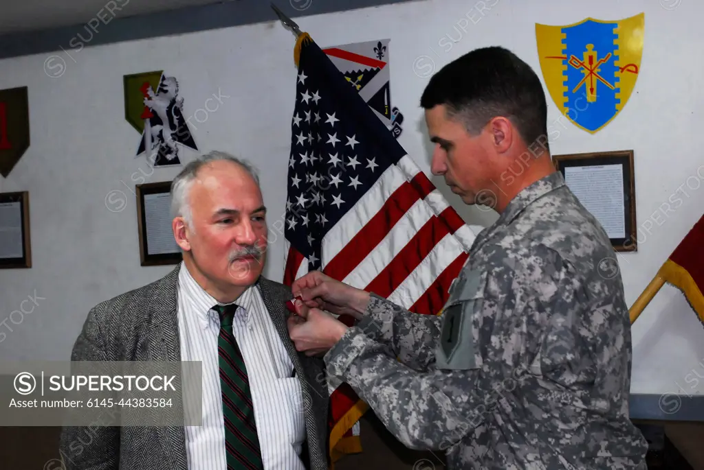 Col. Joseph Martin, commander, 2nd Brigade Combat Team Dagger, 1st Infantry Division, Multi-National Division - Baghdad, pins the Superior Civilian Service Medal on John Crihfield, a foreign service officer with the United States Agency for International Development, embedded with the Dagger Brigade, in a ceremony on Dec. 19. Crihfield, who has worked here since December 2006, worked with Iraqi institutions in governance and economics.