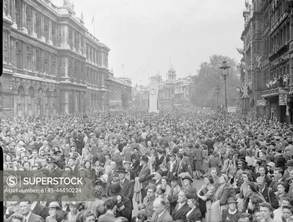 Ve Day Celebrations in London, England, UK, 8 May 1945 Huge crowds of people are gathered in Whitehall to listen to Churchill's Victory speech and to celebrate Victory in Europe Day. The crowd is a mix of service personnel, civilians and children. Behind them can be seen the Cenotaph. People line the balconies of the buildings on the right hand side of the road. This photograph was taken from the Parliament Square end of Whitehall, looking past the Cenotaph towards Trafalgar Square.