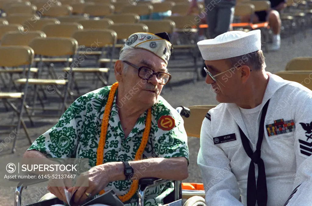 Cryptologic Technician 1ST Class F. Scott Wilson sits beside Raymond Sandlin prior to the start of the Hawaii Remembrance Day observation marking the 50th anniversary of the Japanese attack on Pearl Harbor. Sandlin was an Army private stationed at Hickam Air Field on December 7, 1941. Base: Naval Station, Pearl Harbor State: Hawaii(HI) Country: United States Of America (USA)