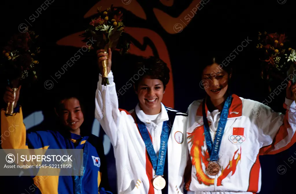 Nancy Johnson, of the US, raises her hands with Cho-Hyun Kang of South Korea (Left), and Jing Gao of China (Right), during the medal ceremony in which Johnson won the gold medal followed by Kang and Goa in the Women's 10-Meter Air Rifle Competition at the 2000 Olympic games in Sydney, Australia. Base: Sydney State: New South Wales Country: Australia (AUS)