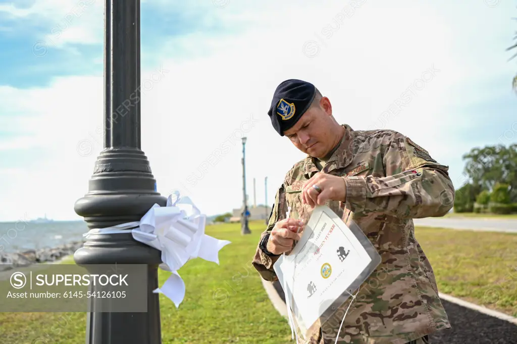 U.S. Air Force Master Sgt. Steven Koster, 6th Security Forces Squadron noncommissioned officer in charge of readiness, places a sign with a fallen veteran during the Second Annual Memorial Day Remembrance event at MacDill Air Force Base, Florida, May 25, 2022. Over 75 signs and ribbons were placed to honor fallen service members