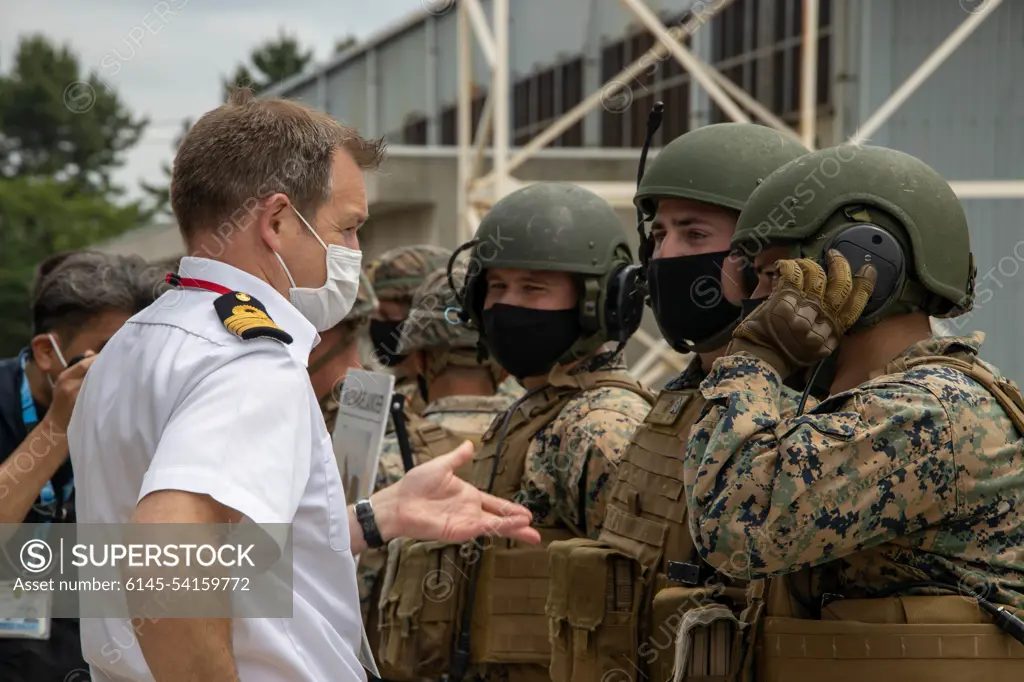 Royal Navy Capt. Dan Thomas, left, deputy commander and Chief of Staff Littoral Strike Group, interacts with U.S. Marines with III Marine Expeditionary Force during a capabilities demonstration, as part of the Pacific Amphibious Leaders Symposium, Camp Kisarazu, Japan, June 16, 2022. This iteration of PALS brought senior leaders of allied and partnered militaries together to discuss amphibious force readiness, expeditionary advanced base operations, intermediate force capabilities, and ways to improve interoperability between partners within the Indo-Pacific region. A total of 18 participating delegations from Asia, Australia, Europe, South America, and North America participated in the symposium.