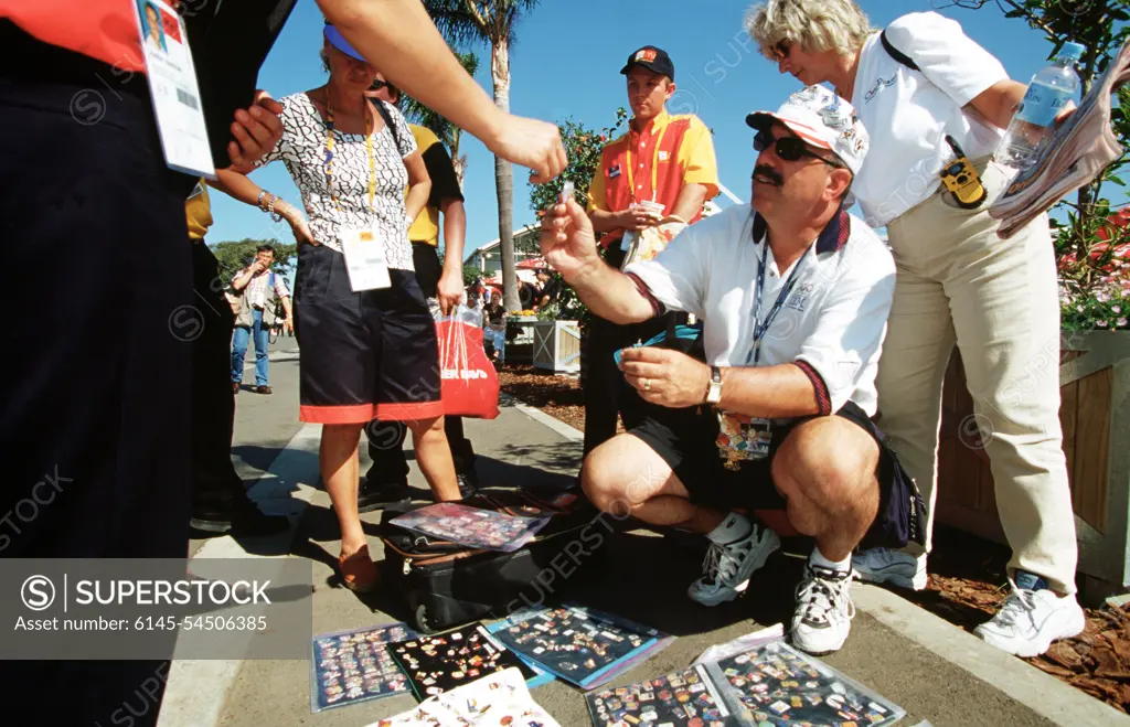 American Bob McKeon, of Poway, California (Kneeling), said the Sydney Olympics is his seventh. McKeon, an avid pin trader and collector, says he brought 20,000 of his 100,000 pin collection to trade with during the sydney 2000 Olympics. Numerous US Department of Defense personnel (Not shown) are taking part in the Olympics, from coaches and support staff to athletes competing in various venues. Base: Sydney State: New South Wales Country: Australia (AUS)