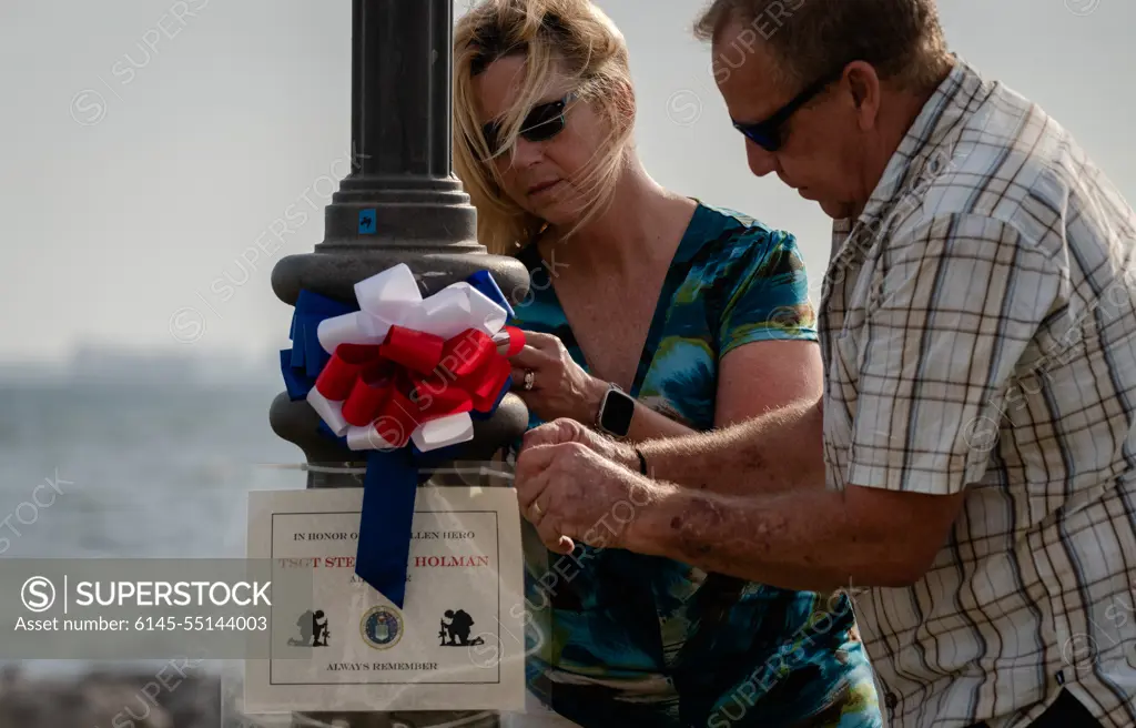 Debra and Gary Holman, surviving family of Tech. Sgt. Steven Holman, place amemorial sign for their son on a lamp post at MacDill Air Force Base,Florida during the Second Annual Memorial Day Remembrance event May 25,2022. Volunteers from MacDill AFB and the surrounding community cametogether to place 75 signs around MacDill to honor fallen service members.